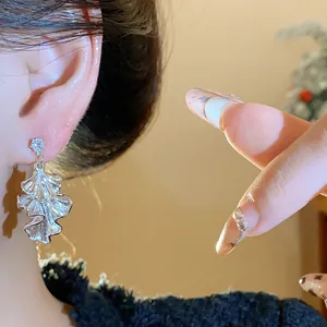 Close-up of silver ruffled leaf drop earrings worn on ear for detail