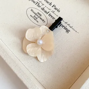 Close-up view of an elegant cream white flower hair clip with pearl and rhinestone