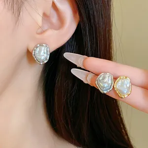Close-up of French vintage wrinkled metal stud earrings with artificial pearl detail.