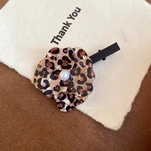 Close-up detail of a floral leopard print hair clip featuring a white center pearl