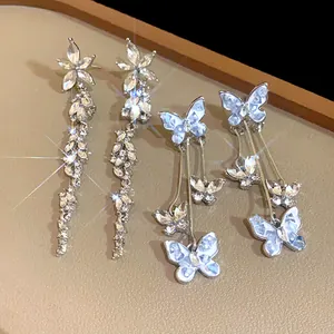 Detail view of elegant silver needle drop earrings with crystals and butterfly motifs