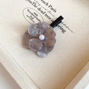 Macro view of an elegant flower hair clip with pearl center and gray marbled resin petals.