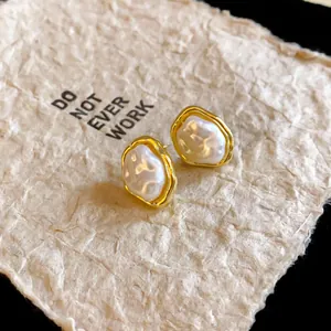 Macro view of French vintage faux pearl earrings with irregular gold rim detailing