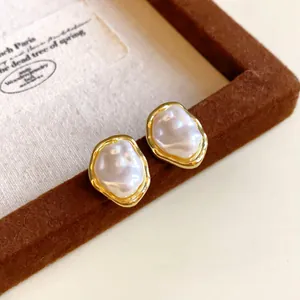 Detail of vintage French baroque pearl earrings featuring irregular wavy gold bezels