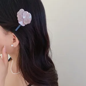 Elegant pink acetate flower hair clip with pearl detail shown on a female model