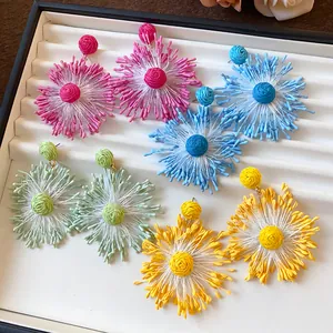 Vibrant handmade woven firework flower earrings in multiple colors on a display tray.