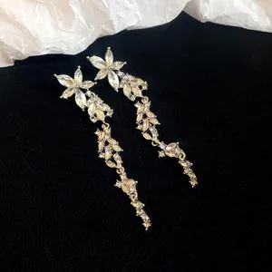 Exquisite long silver drop earrings with floral crystal clusters on a black background