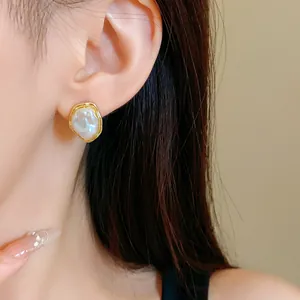 Detail view of French retro stud earring with irregular gold pleated border and pearl