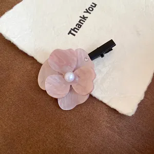 Close-up of a pink marble floral hair clip with pearl center and rhinestone detail