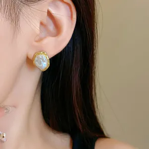 Close-up detail of French vintage irregular faux pearl earrings worn on the ear.
