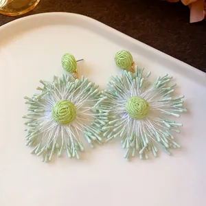 Close-up detail of handmade woven light green and white flower firework resort earrings