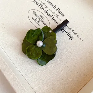 Detailed macro shot of a green layered flower hair clip with center pearl