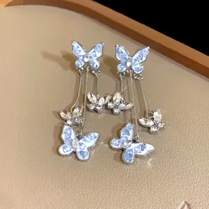 Close-up of elegant long butterfly dangle earrings with crystals and blue finish