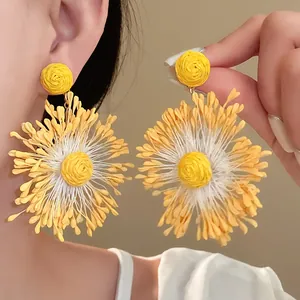 Detailed view of yellow handmade woven flower earrings featuring a vibrant holiday vibe