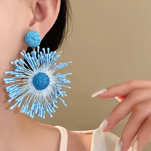 Detailed view of large blue handmade woven firework flower earrings worn by an Asian model