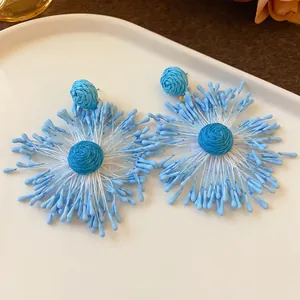 Detailed macro view of handmade blue woven fireworks earrings for vacation style