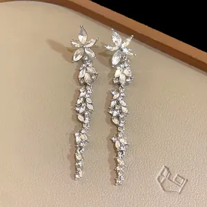 Detail shot of long silver crystal tassel earrings with sparkling floral patterns.