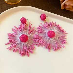Detailed view of pink handmade woven firework earrings with vibrant floral design