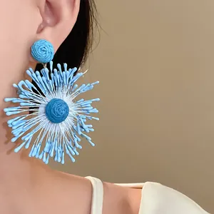 Detailed macro view of hand-woven blue flower firework earrings in a chic holiday style