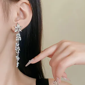Close-up of elegant long dangling flower earrings with shimmering crystals on model
