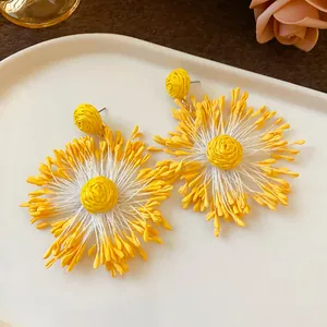 Close-up detail showing texture of yellow handmade woven flower earrings with steel needles
