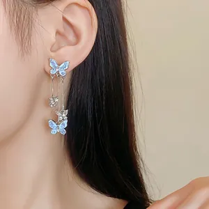 Detailed macro view of elegant silver butterfly tassel earrings worn by a model.