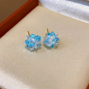 Macro view of sparkling blue and white crystal flower stud earrings in a jewelry gift box