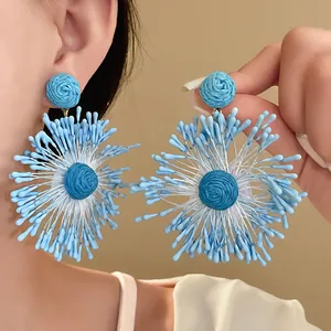 Detail of handmade blue woven flower earrings with a unique firework shape design