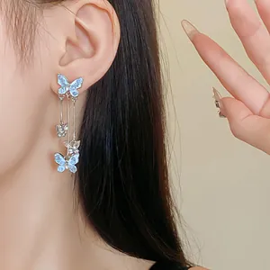 Detailed view of elegant silver needle butterfly drop earrings with blue crystal accents