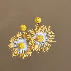 Macro view of vibrant yellow handmade woven flower earrings with intricate fiber petal textures