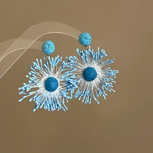 Detailed shot of handmade blue woven flower firework earrings on a clear stand