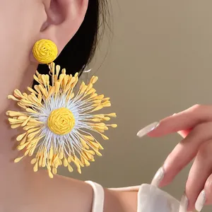 Close-up of handmade woven yellow flower earrings with firework pattern on model