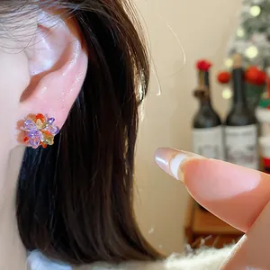 Macro detail shot of a multicolored crystal flower stud earring on an ear with bokeh background
