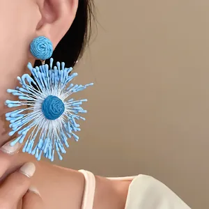 Detailed view of vibrant blue handmade woven flower earrings featuring a firework design