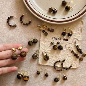Various vintage tiger eye stone earrings with gold metal accents on textured background
