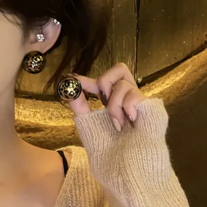 Nahaufnahme von Vintage-Ohrsteckern mit Leopardenmuster, getragen von einem Model.