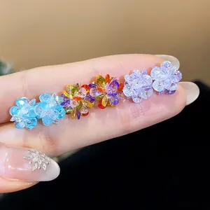 Close-up macro view of vibrant colorful crystal flower stud earrings held on a finger