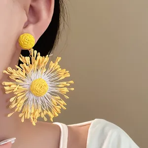 Close-up of yellow handmade woven flower earrings in a vibrant vacation style.
