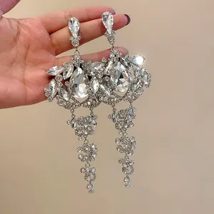 Detailed macro view of large silver tassel earrings with sparkling waterdrop crystals.