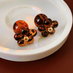 Detailansicht von Retro-Blumenohrringen mit Leopardenmuster auf einer weißen Schale