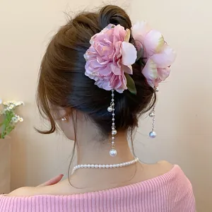 Detail view of an elegant floral hair claw clip with pearl tassels on model.