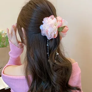 Detailed view of elegant pink fabric flower hair clip with pearl tassels on model