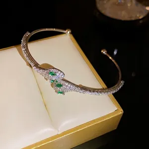 Lujosa pulsera abierta con forma de serpiente plateada con circonitas y ojos de piedra verde
