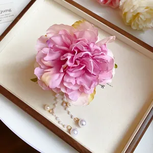 Close-up of a pink fabric flower shark clip with delicate hanging pearl tassels for bun hair