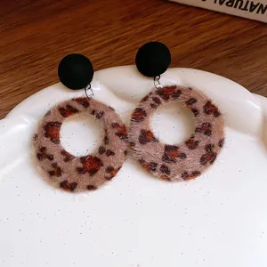 Nahaufnahme von runden Retro-Ohrringen mit Leopardenmuster und schwarzen Samtsteckern.