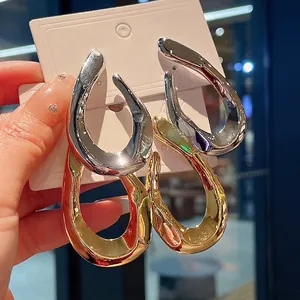 Chunky twisted gold and silver hoop earrings with a minimalist metal finish