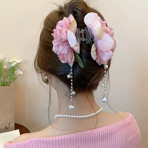 Elegant detail view of a pink fabric flower hair claw clip with dangling pearl tassels.