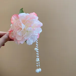 Close-up of pink fabric flower hair clip with dangling white pearl tassels