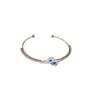 Elegante brazalete abierto de serpiente en oro con circonitas brillantes y piedras verdes