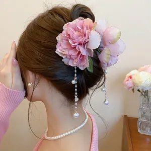 Close-up of pink fabric flower hair claw with elegant hanging pearl tassels
